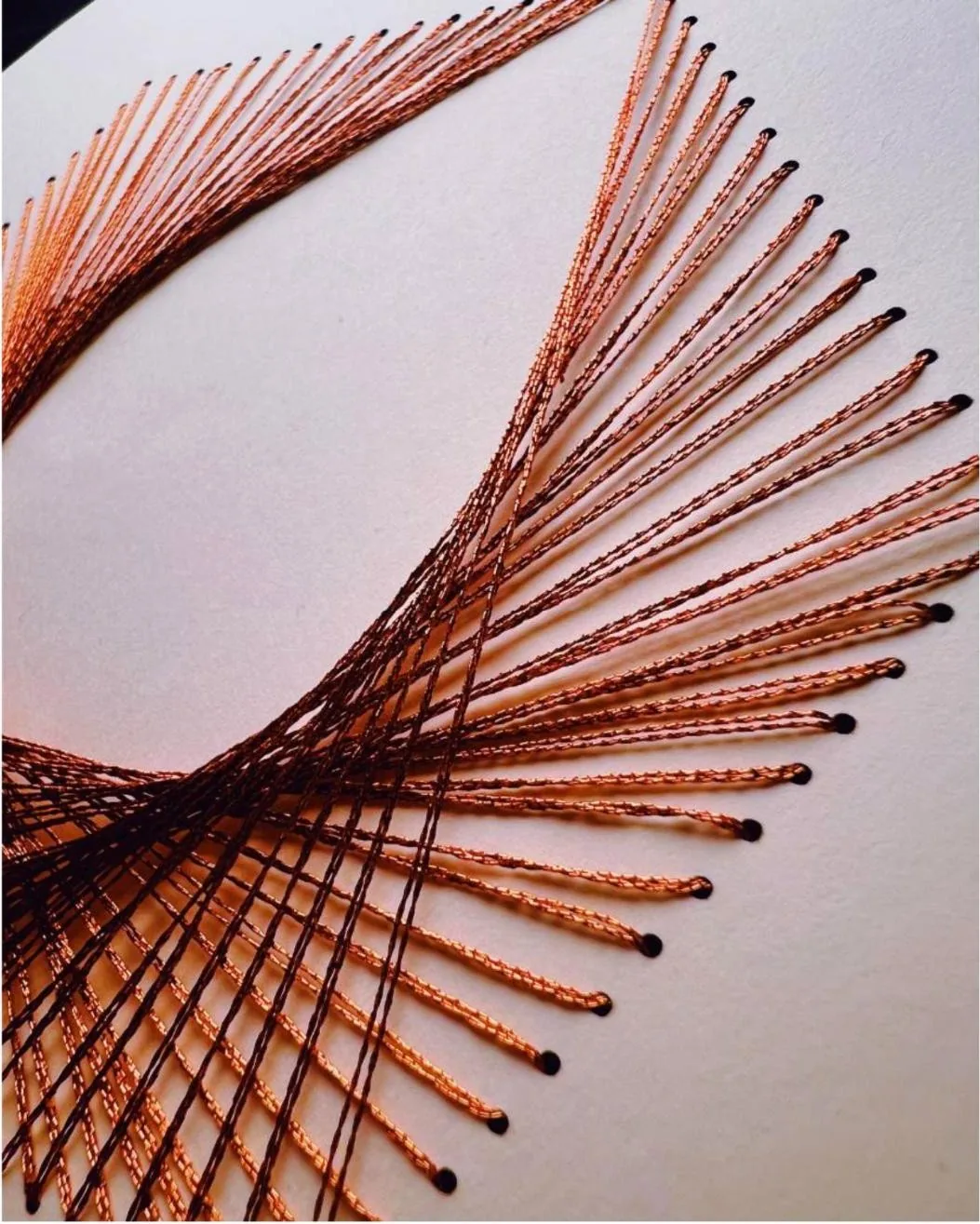 Close-up of copper thread stitched between pierced points forming a curved envelope